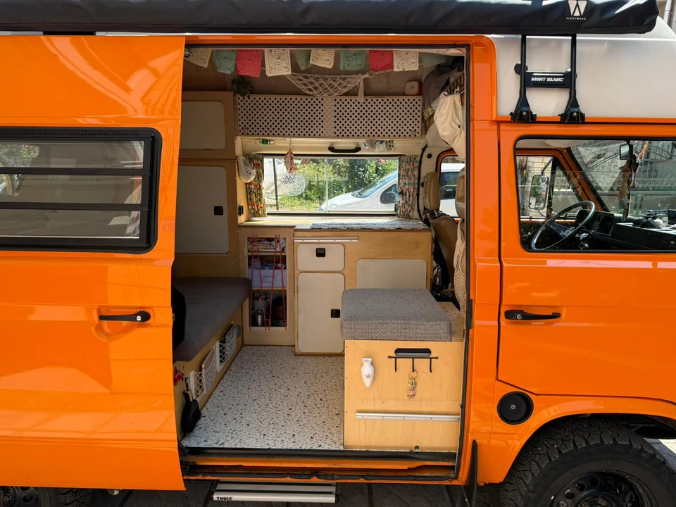 Blick durch die offene Schiebetür auf den individuellen Innenausbau des orangefarbenen VW T3