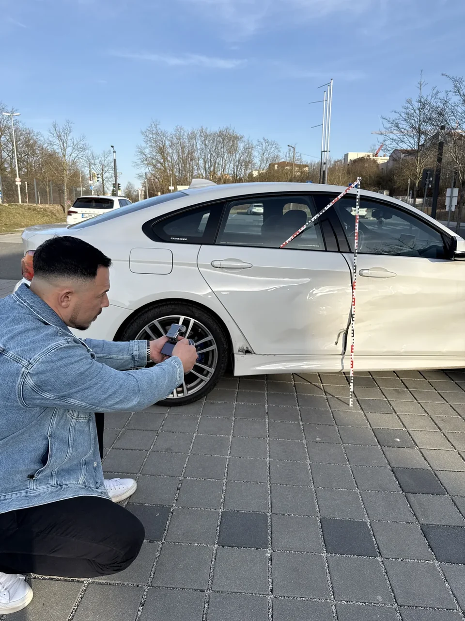 Oleg Tashin dokumentiert den Seitenschaden eines weißen BMW