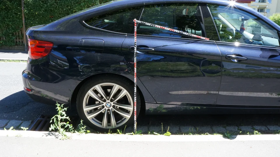 Schadenaufnahme an der Fahrzeugseite mit Maßstäben
